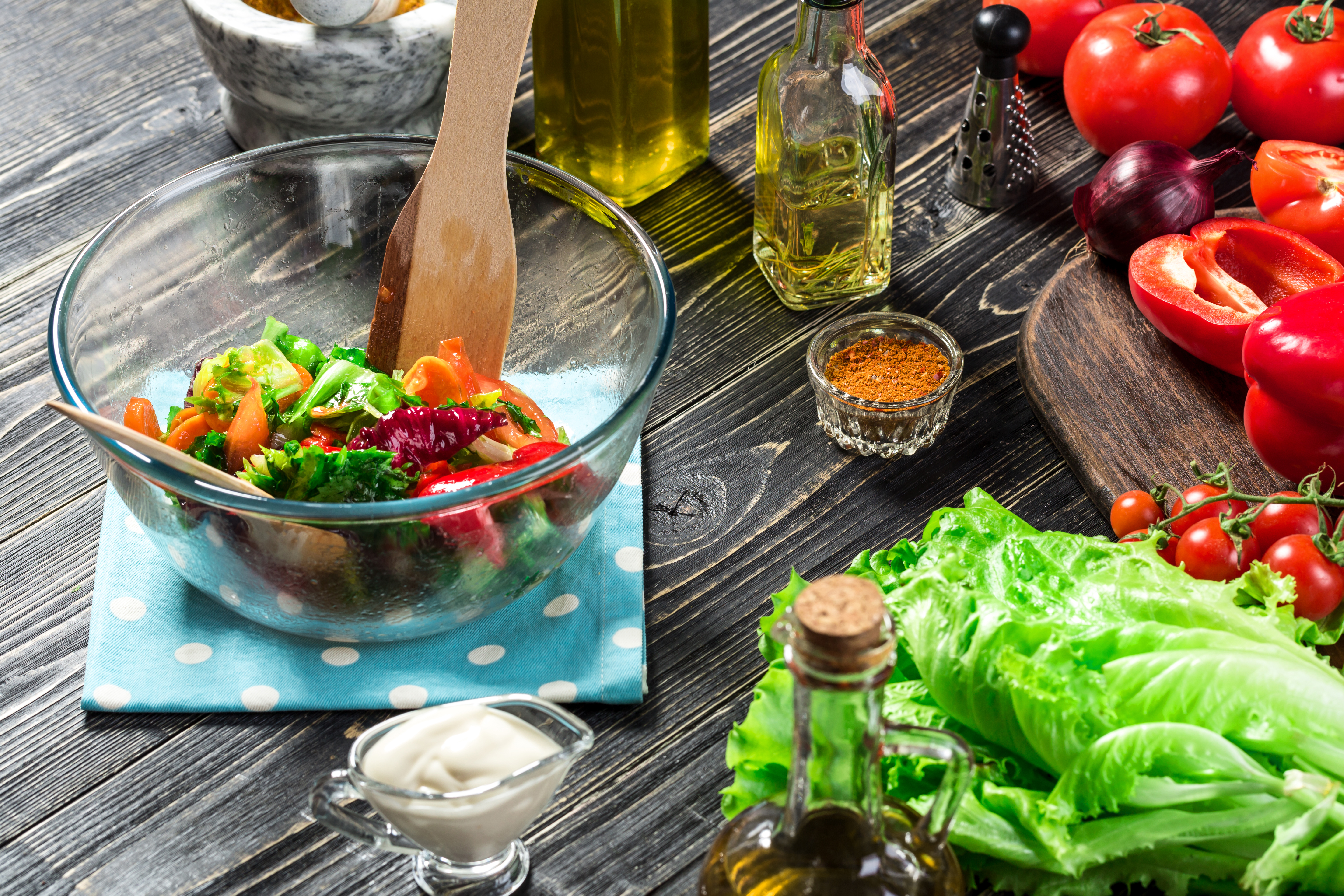 Preparing salad with fresh vegetables and olive oil.